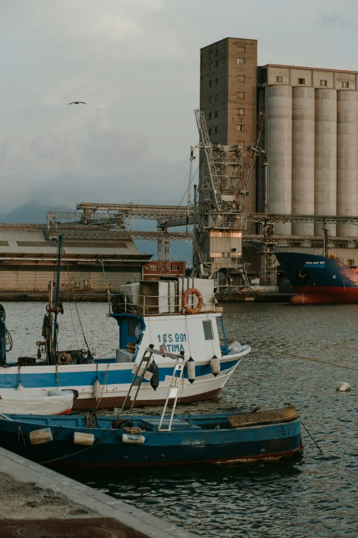 an industrial boat docked at a pier with grain mills in the background