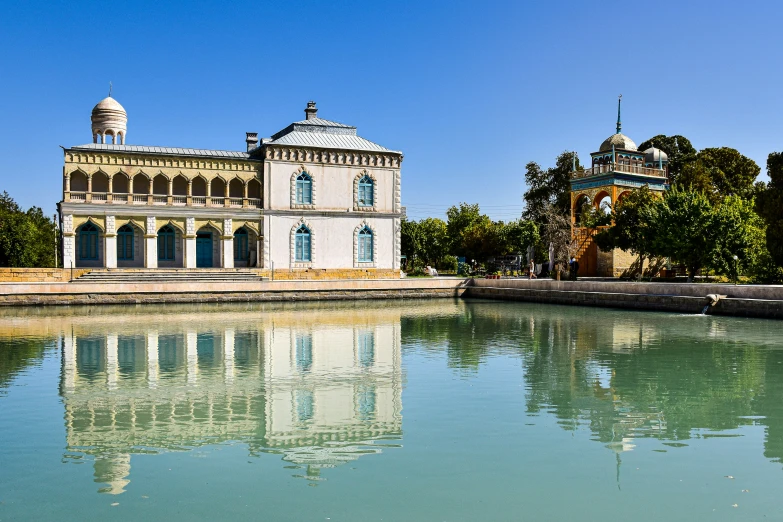 an old house sitting next to a lake in the middle of a park