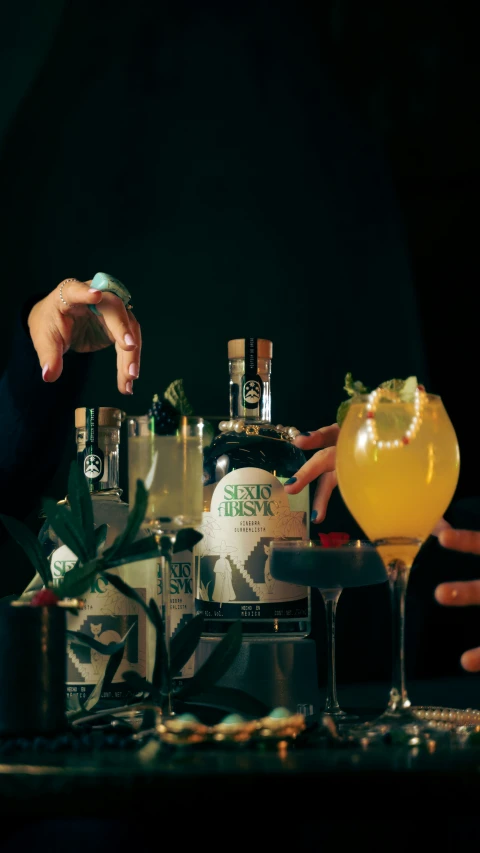 two women are reaching for a cocktail in front of some bottles