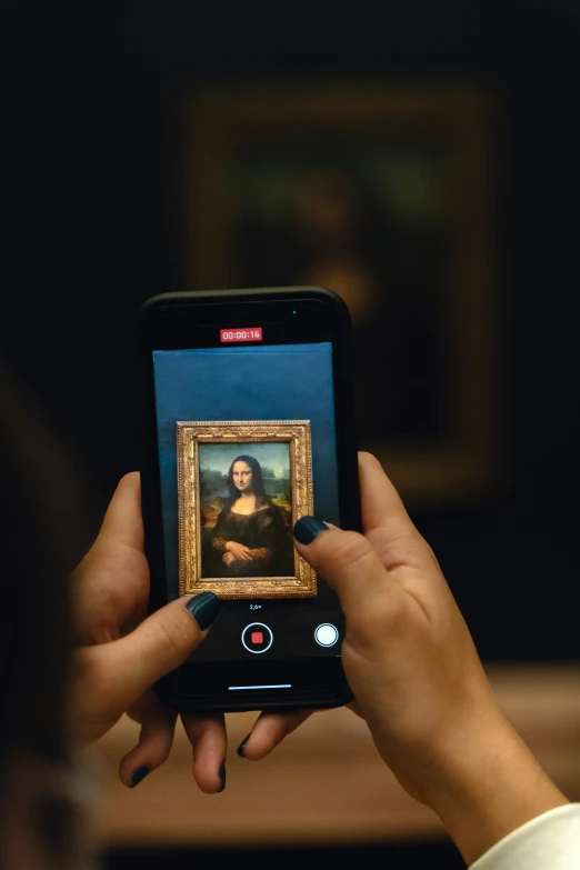 a woman is holding up a picture with an iphone in her hand