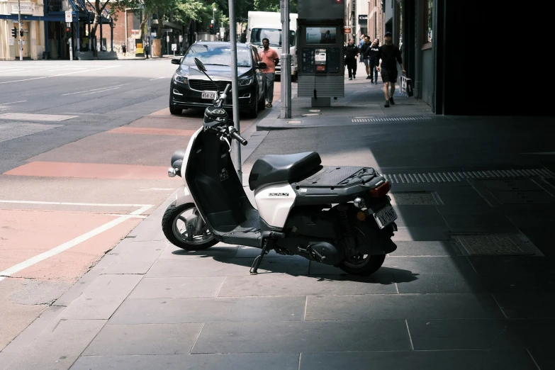 the moped is parked next to the curb