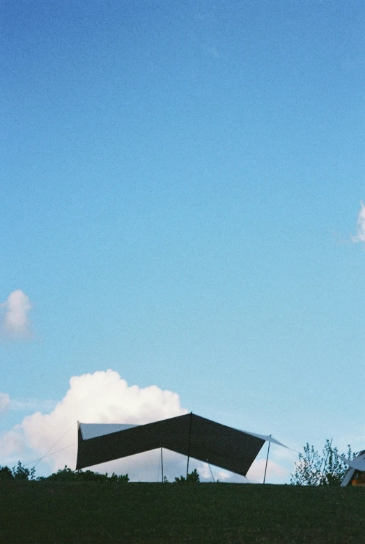 a building with a large rectangular roof sitting in the middle of the grass