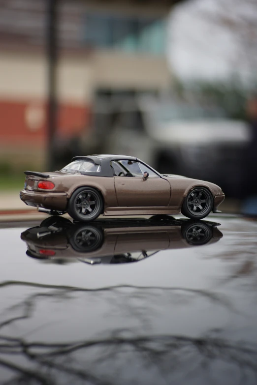 small model car on reflective surface in city setting