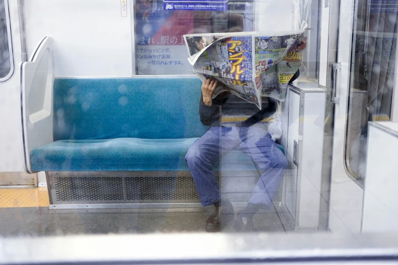 the woman is reading the newspaper while sitting on the train