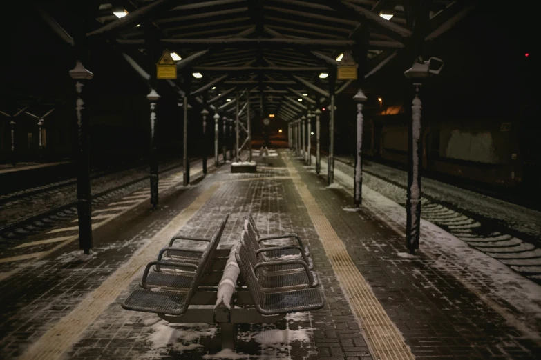 empty benches on the platform at night next to a railroad track