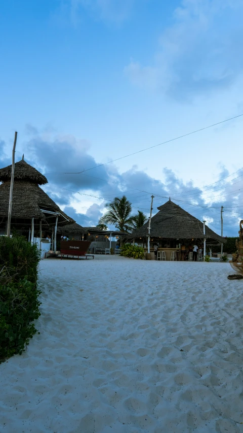 a po of beach area with grass huts and trees