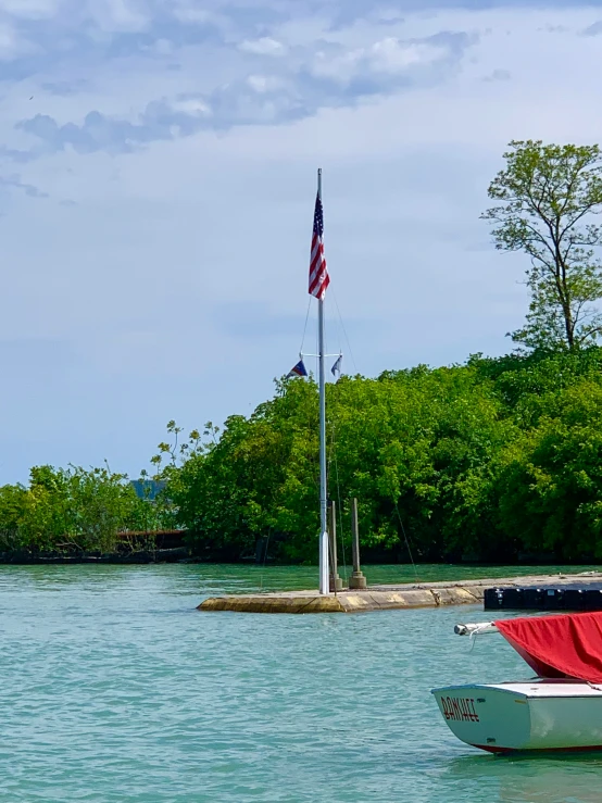 a boat on the water near a flag pole and a dock