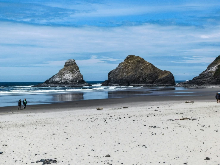 people on a beach with some rocks in the water