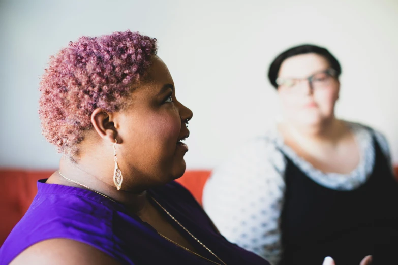 a woman with pink hair and glasses standing near a woman with black hair