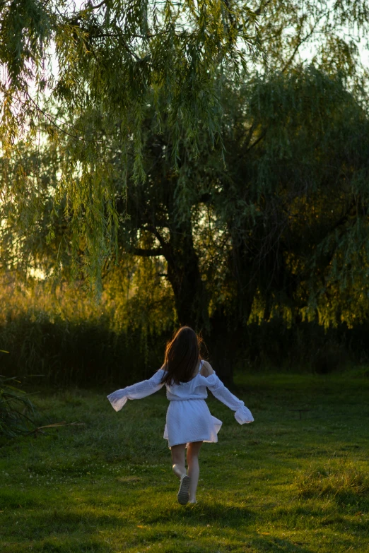 a little girl in a white dress playing outside