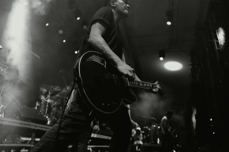 a man holding a guitar and standing in front of an audience