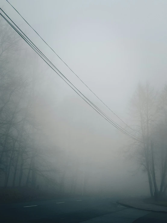 a power line on a foggy day with telephone wires hanging in the distance