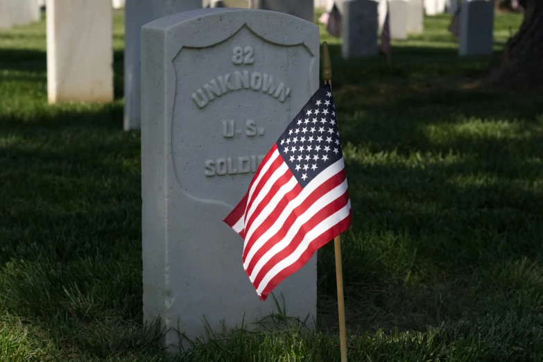 a flag laying at the base of a military tombstone