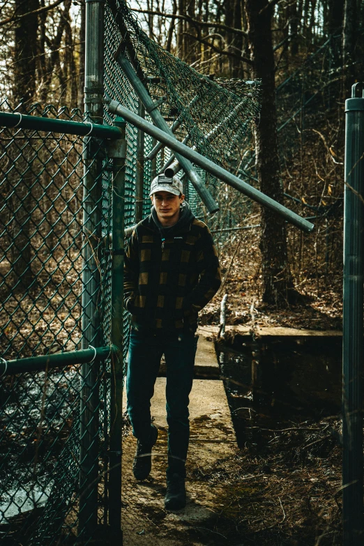 a man standing in a green cage in the woods