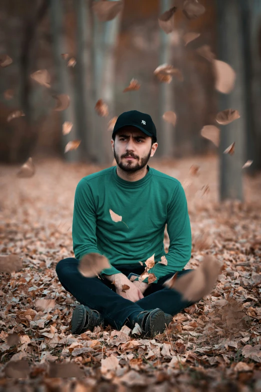 a man sitting in the leaves with his eyes closed