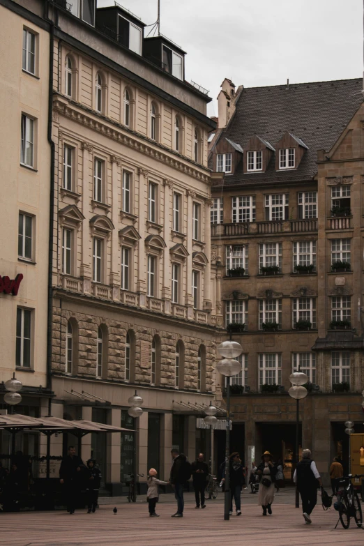 several people walk around the plaza near an old building