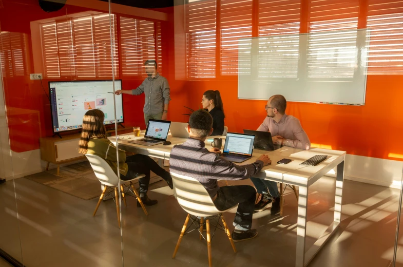 a group of people sitting around a table in front of laptop computers