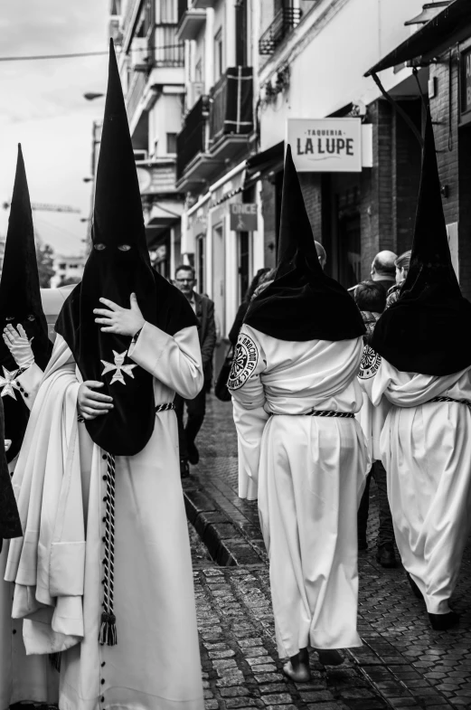 several people in black and white walking on the sidewalk