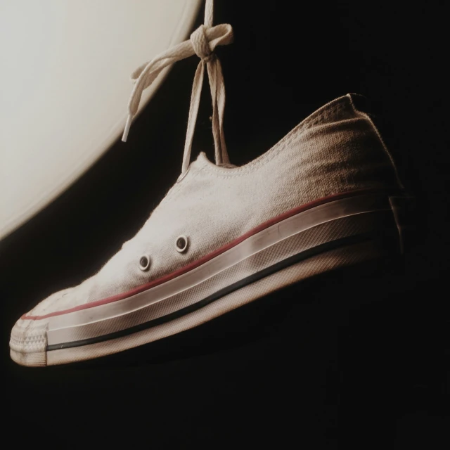 a sneaker with white and red striped detail sits on a white background