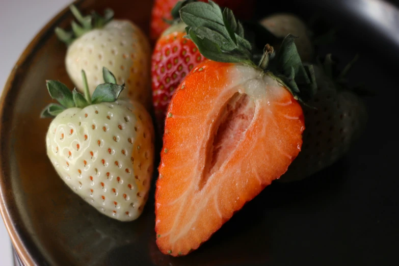 three strawberries sit on a brown plate