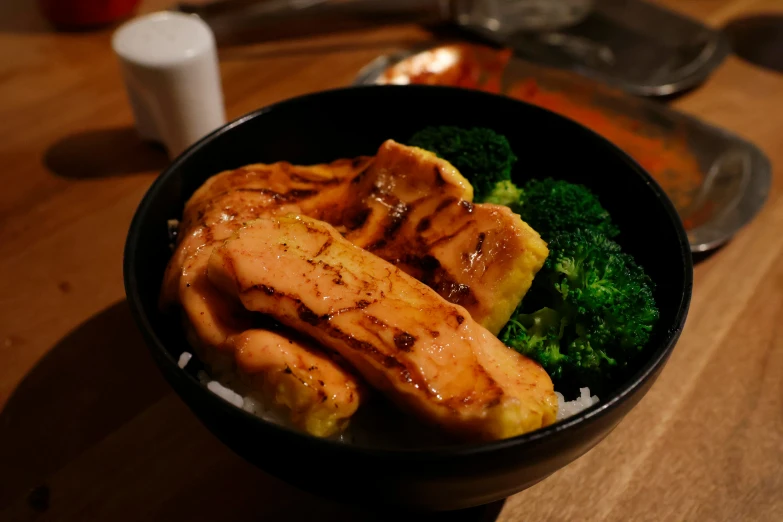 a bowl of chicken and broccoli with sauce on top