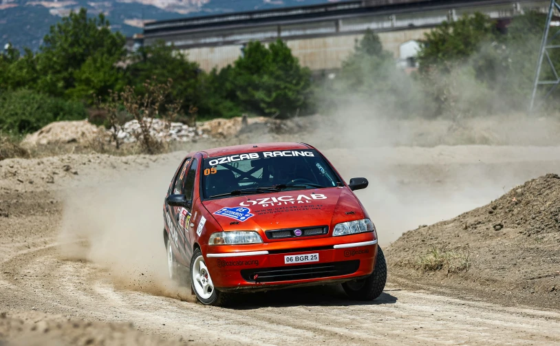 a red car drives down a dirt road