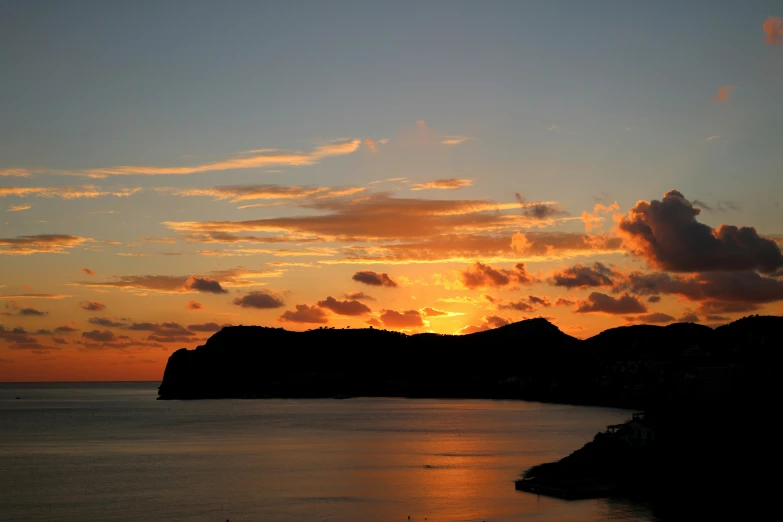 an orange sunset is seen over a body of water