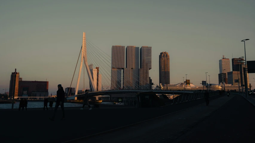 the sun sets behind the cityscape with people walking on the road