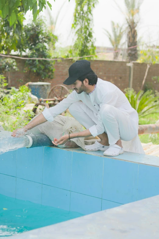 a young man crouching near an empty swimming pool