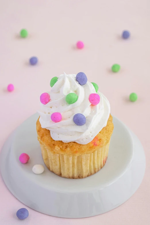 cupcake sitting on top of a plate with sprinkles