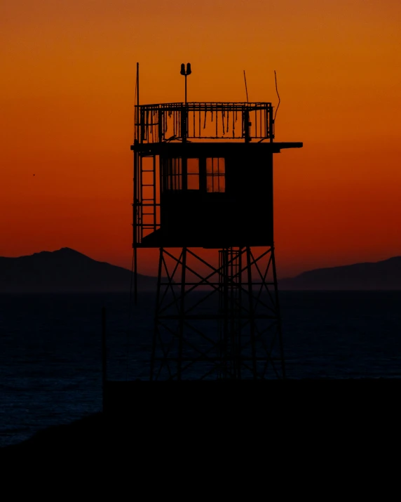 a sunset scene with the silhouette of a lifeguard tower