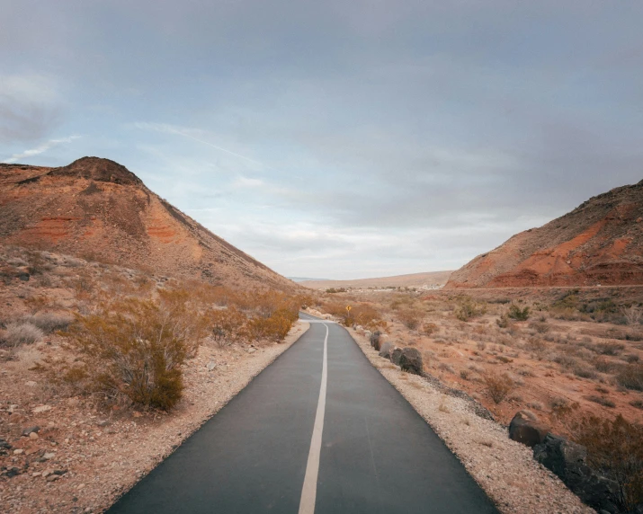 an empty paved road leading into the desert