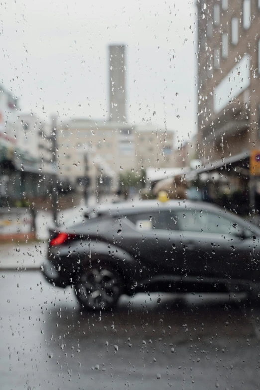 a car sitting in front of some building on a rainy day