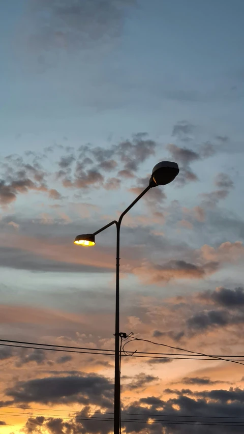 a street lamp with light at twilight in the sky