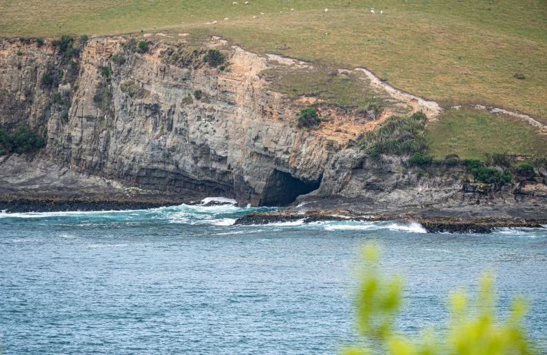 a rocky ocean area with a cave next to it