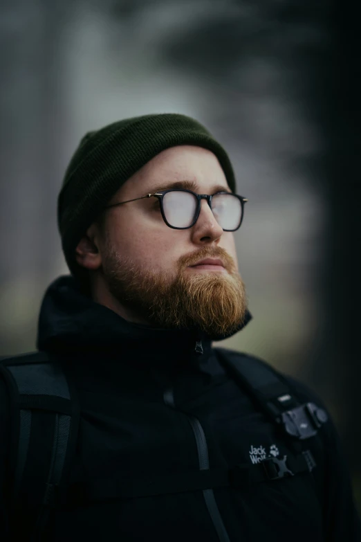 a man wearing glasses and a green beanie