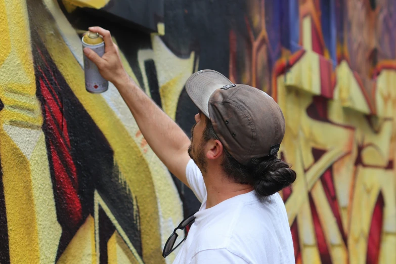 a man with a hat is painting a mural on the side of a building