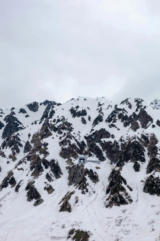 the tops of some snow covered hills with skiiers