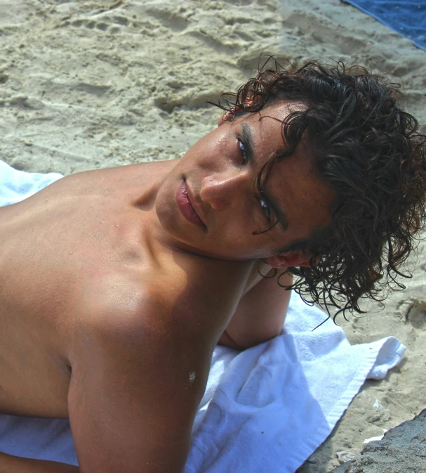 a man laying on top of a towel covered beach