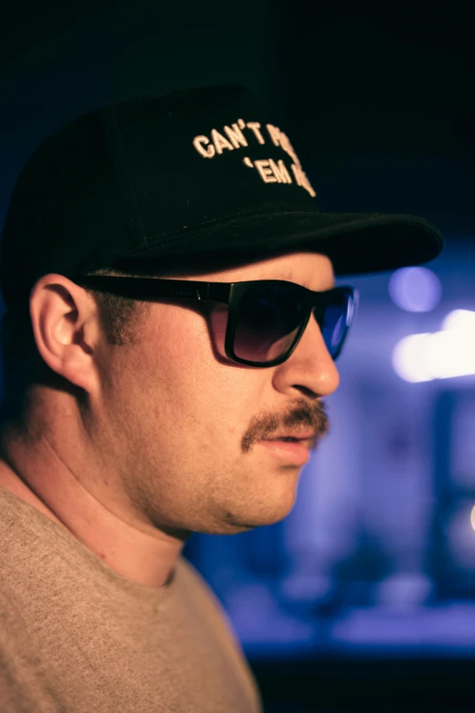 man wearing sunglasses and cap with an embroved message on the cap