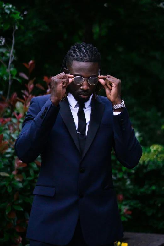 a man in a suit, tie and glasses covers his eyes