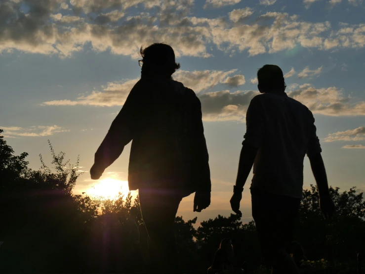 two young men standing together with the sun in the background