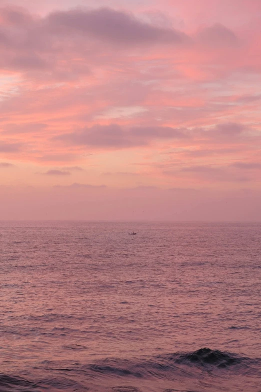 a lone sail boat out on the ocean at sunset