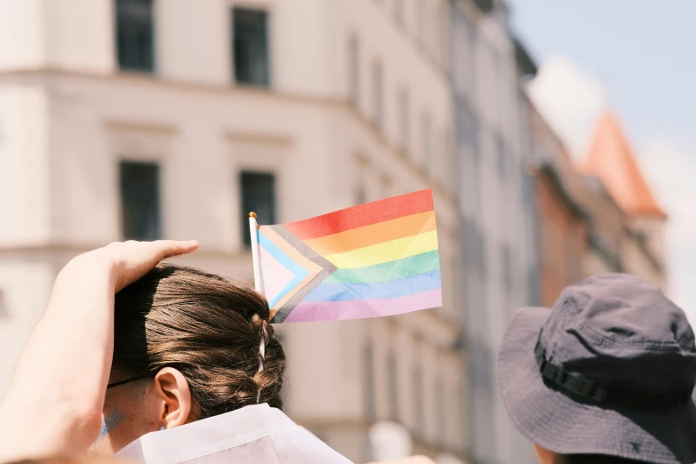 someone holding a rainbow flag in their hands and taking a picture