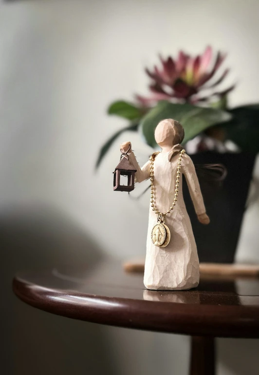 a small wooden figurine holding a light on a table