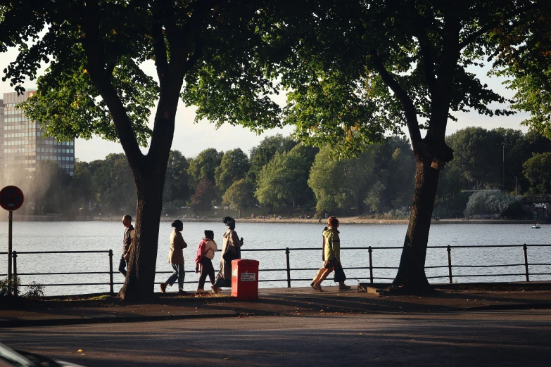 people walking down a path near trees, with water spraying in the background