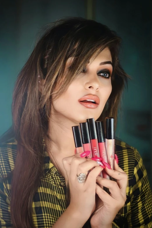 woman in plaid shirt holding lipsticks to her mouth