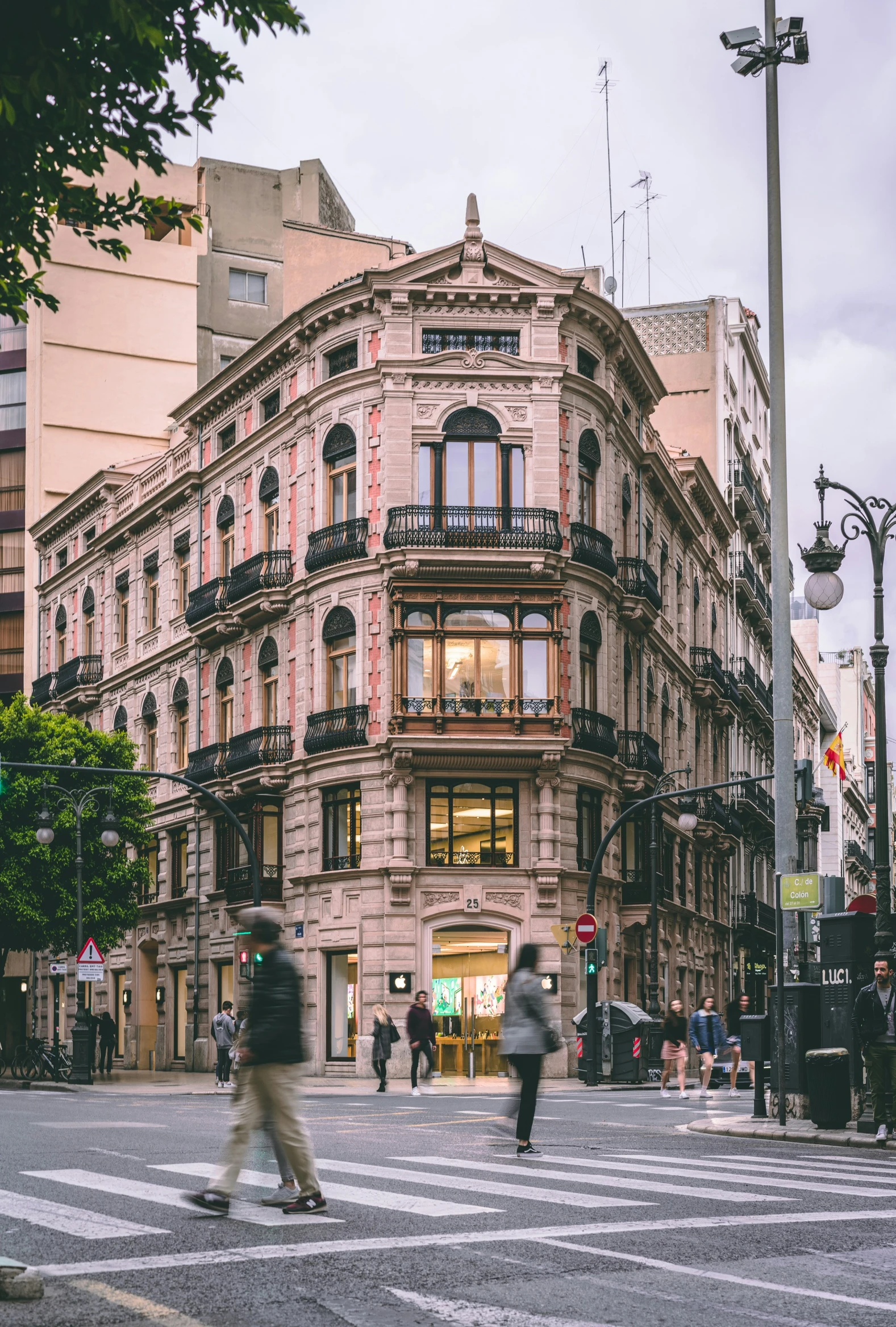 pedestrians walk by an old building and a street corner