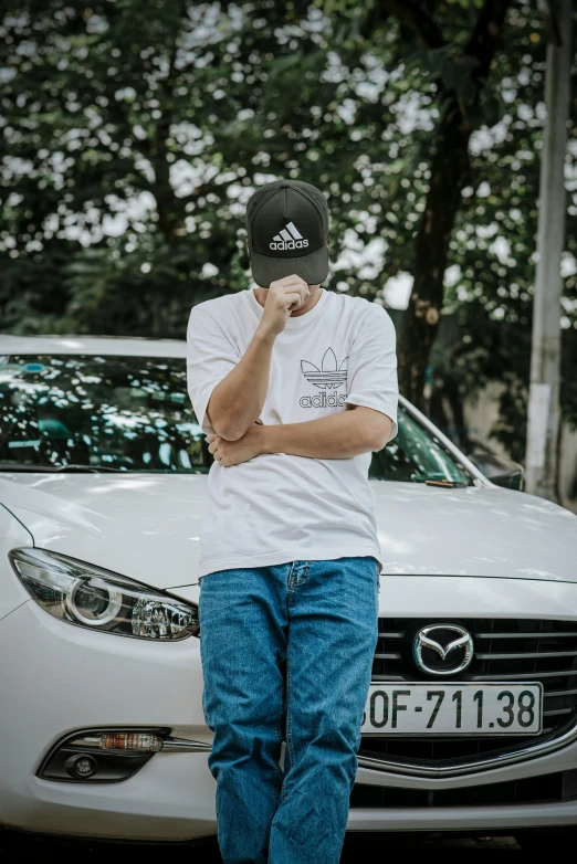 the young man stands near the white car in the parking lot