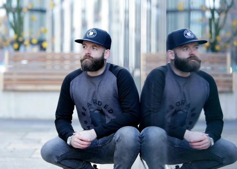 a man sitting on the ground next to another man wearing a hat